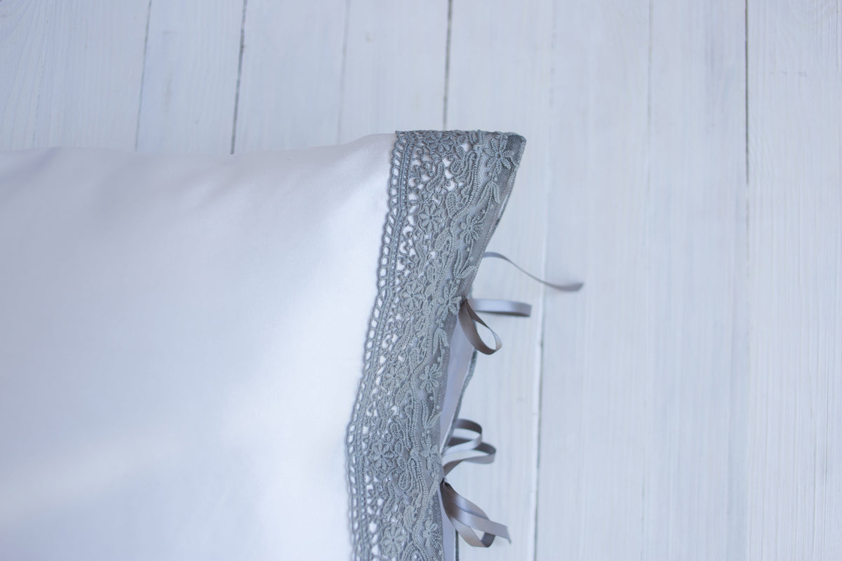Grey lace and ribbon embellish the lustrous silk pillowcase